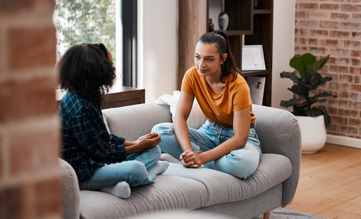 Two friends, talking cross-legged on the sofa