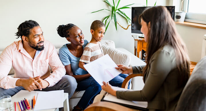 A couple and their child, smiling and talking to a practitioner