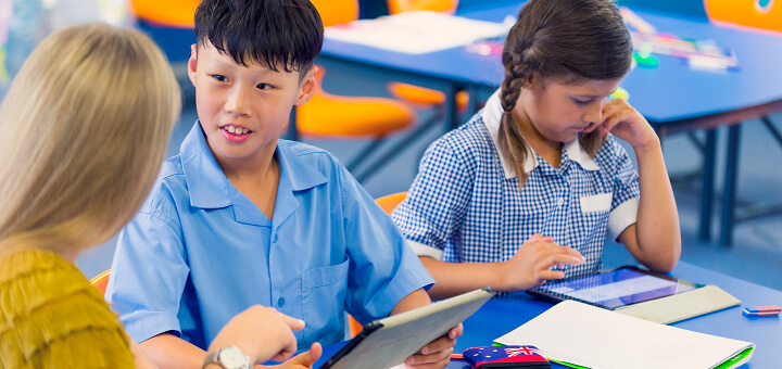 Two children in a learning environment and a teacher talking to one of them