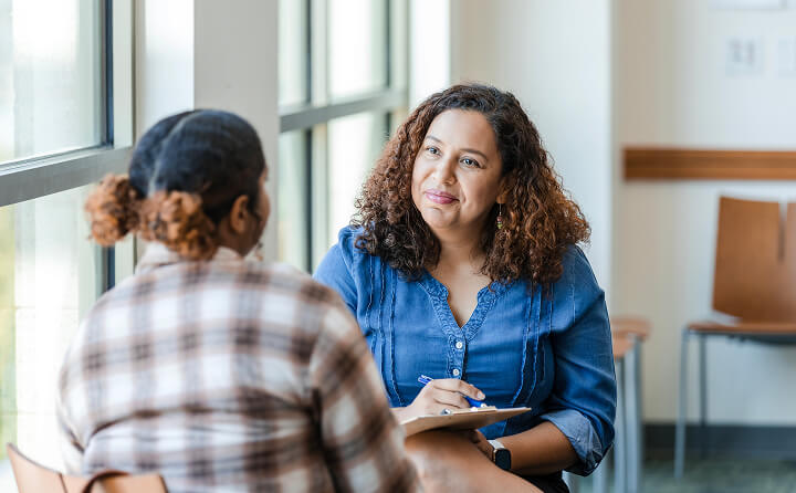 A woman mentoring another and taking notes